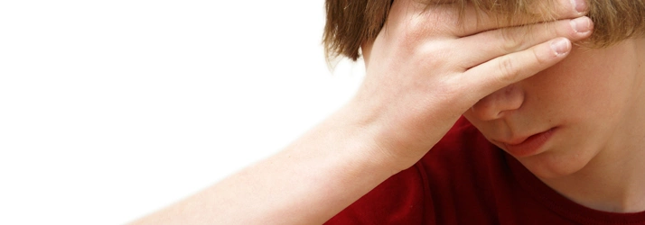 Close-up of a child with hand resting on forehead