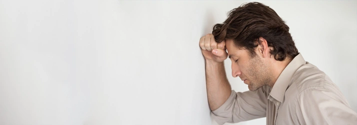 Person leaning against a wall with head resting on hand