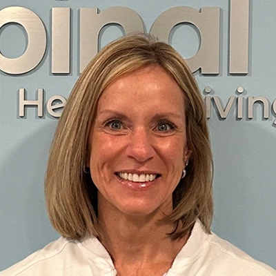 Smiling healthcare professional in front of spinal care clinic sign