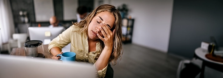 Person sitting at a desk with hand covering face