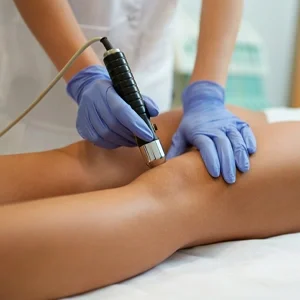 Clinician using a handheld therapy device on a patient’s knee